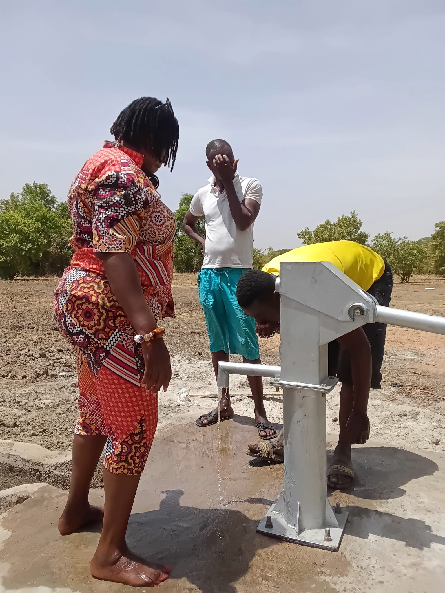 People using the community borehole hand pump in Nakong